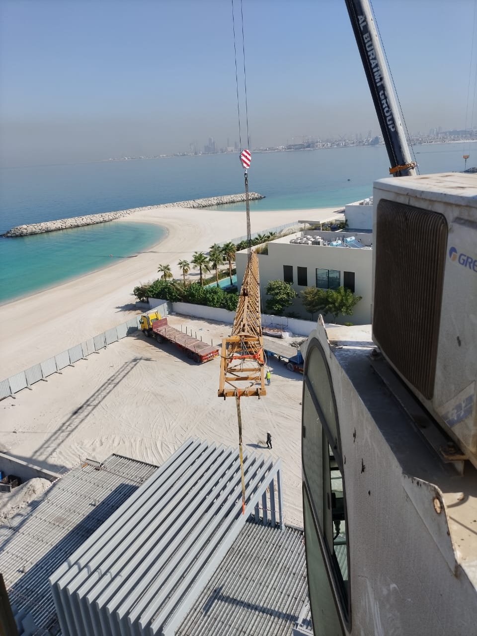 Waterfront crane operation lowering tower crane sections during dismantling support.